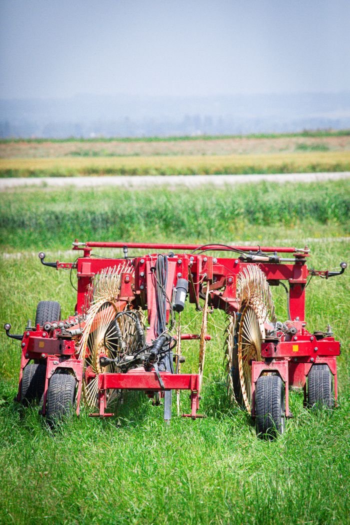 Close-up of red farming equipment on a lush green field in Mont Saint-Michel, Normandy.